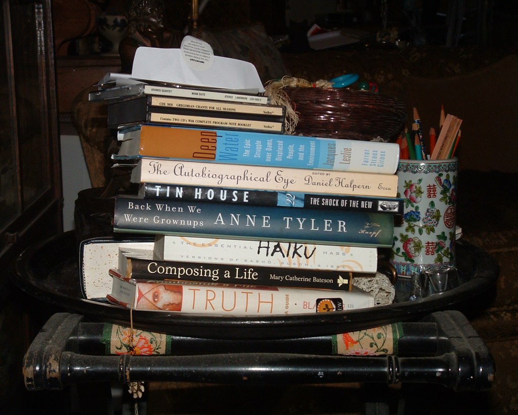 A tall pile of books, with three music cd's on top. The books are novels, books about writing, maybe some poetry.
